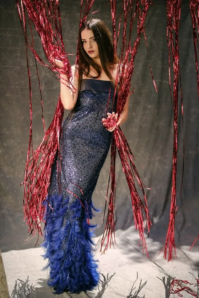 Navy sequin gown with a feathered hem against red cord