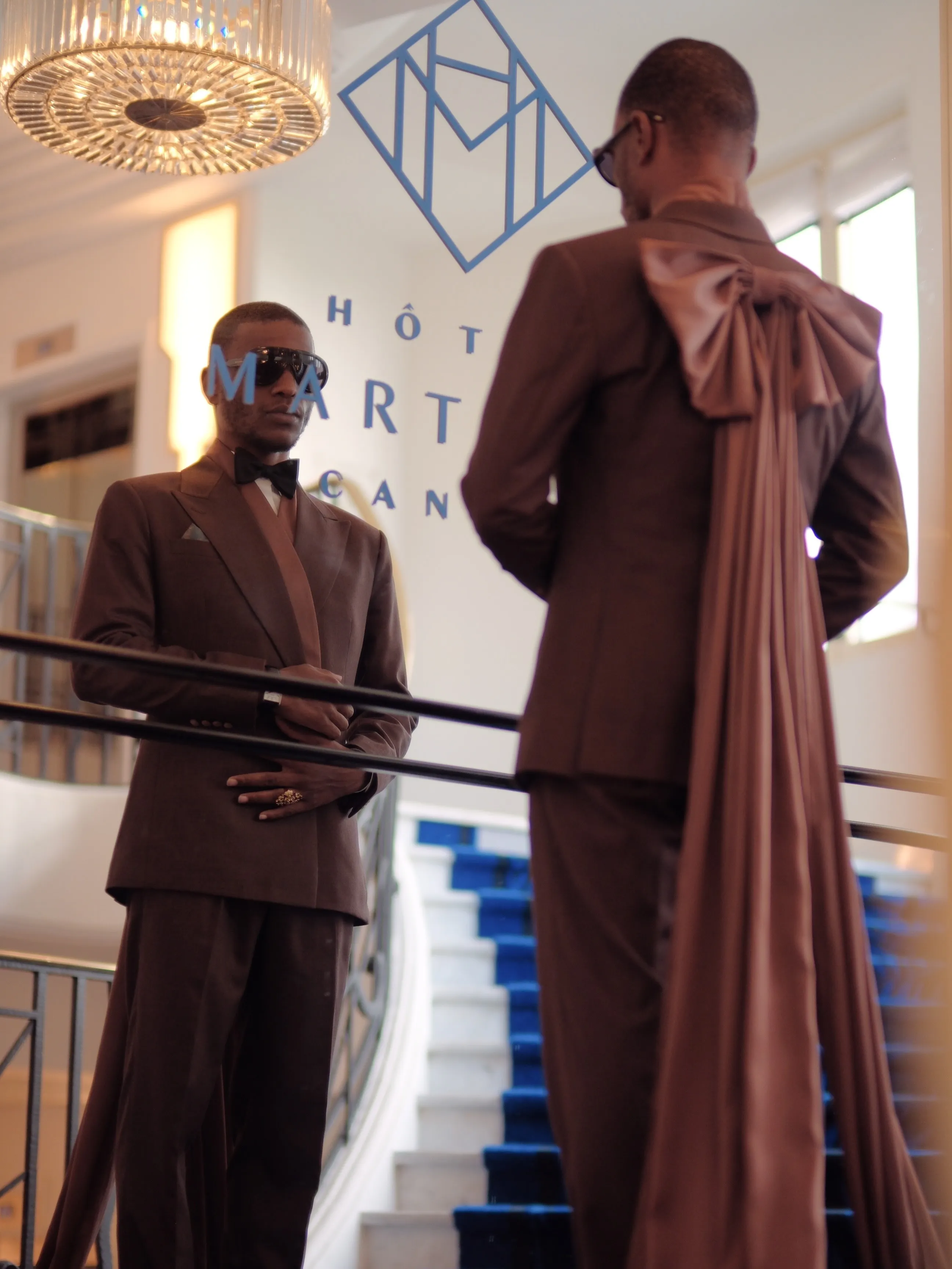 Chocolate satin suit with an oversized bow at the back, on a hotel staircase